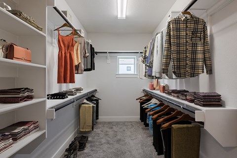 a walk in closet filled with clothes and shoes