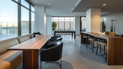 A modern dining area with a long wooden table and black chairs.