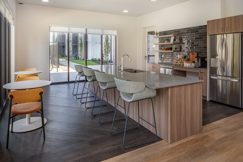 A modern kitchen with a wooden island and grey chairs.