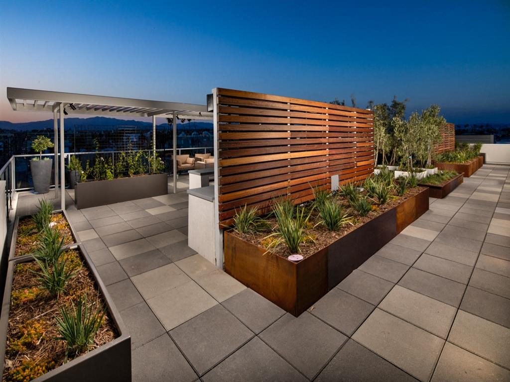 a roof terrace with plants and a wooden fence