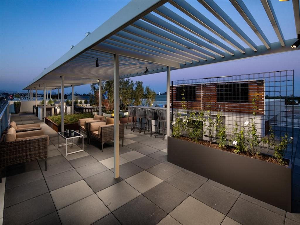 a roof top patio with furniture and a fence