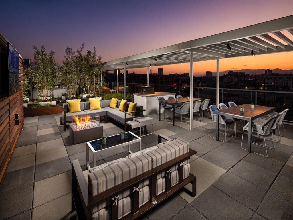 a rendering of a rooftop patio with furniture and a fire pit