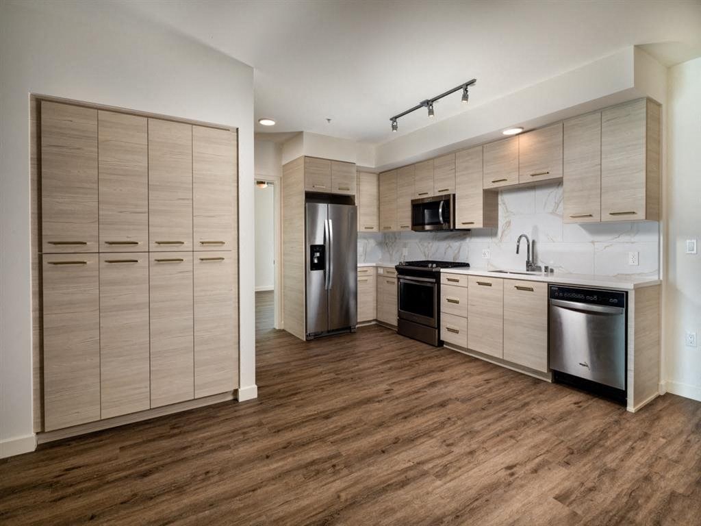 a kitchen with wooden floors and a stainless steel refrigerator