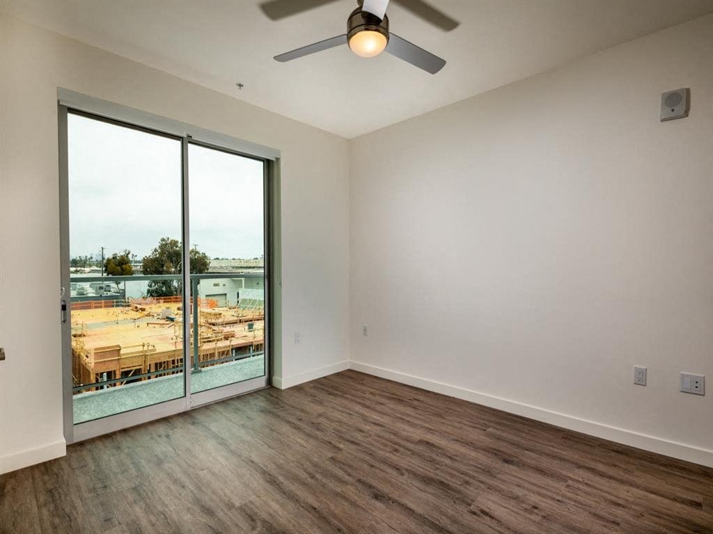 an empty living room with a ceiling fan and a balcony