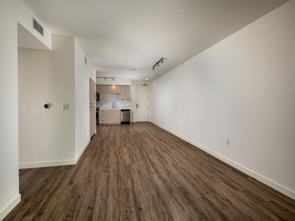 an empty living room and kitchen with white walls and wood floors