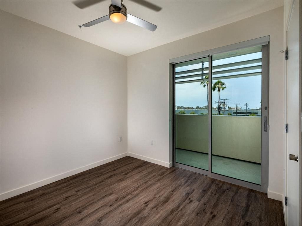 an empty room with a sliding glass door and a ceiling fan