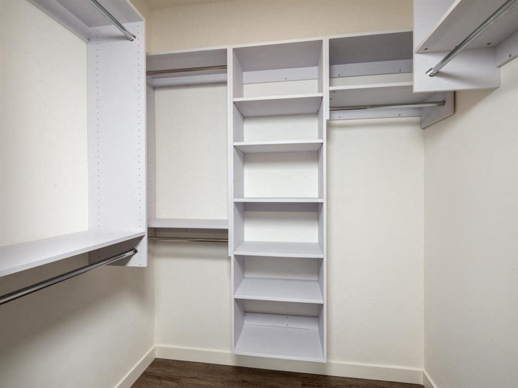 a walk in closet with white shelves and