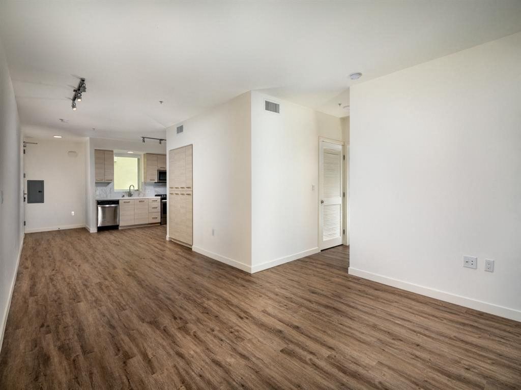 a living room and kitchen with white walls and wood floors