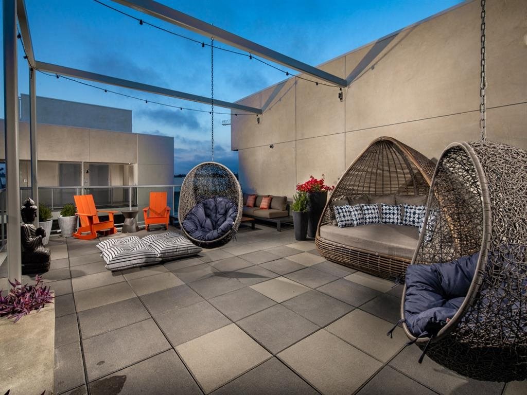 a rooftop patio with chairs and hammocks and a building in the background