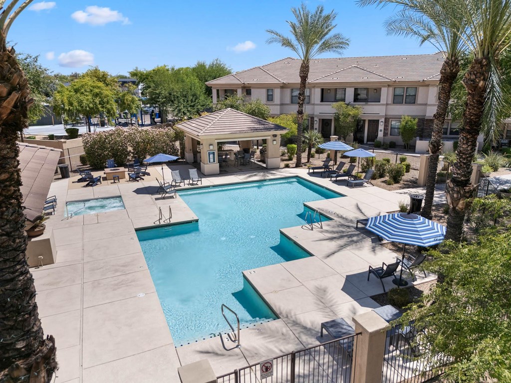 A pool surrounded by palm trees and a building in the background.