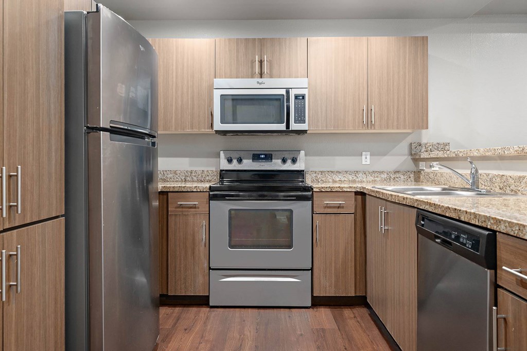 A kitchen with a refrigerator, oven, microwave, and dishwasher.