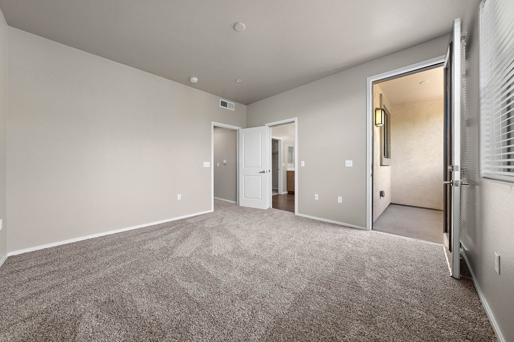 A spacious room with a carpeted floor and a doorway leading to another room.