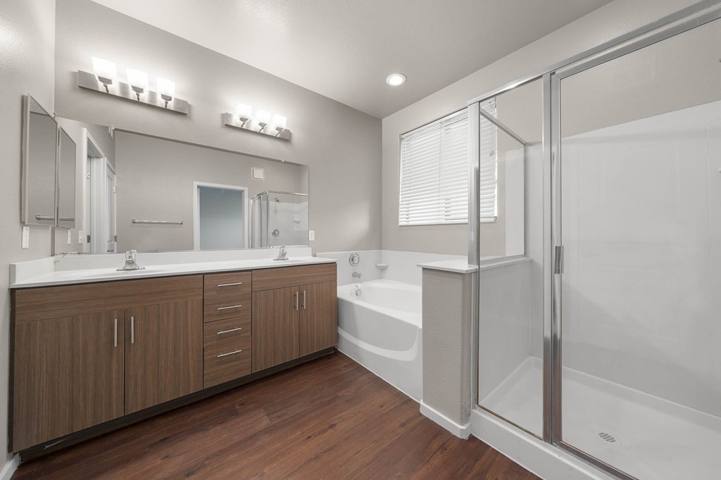 A modern bathroom with a white tub and wooden cabinets.