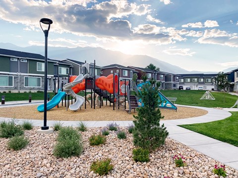 A playground with a slide and a tree in the foreground.
