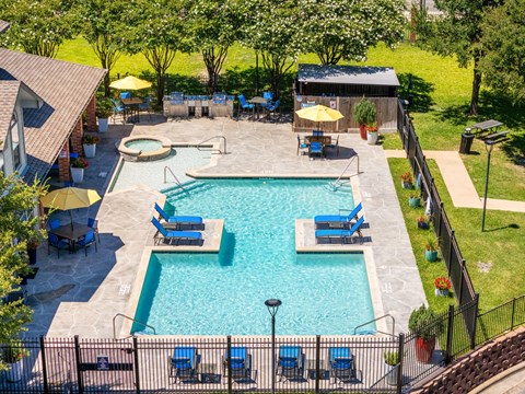 A pool surrounded by a black fence and blue chairs.