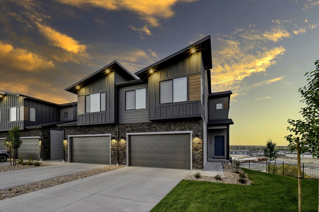a house with two garage doors and a sunset in the background