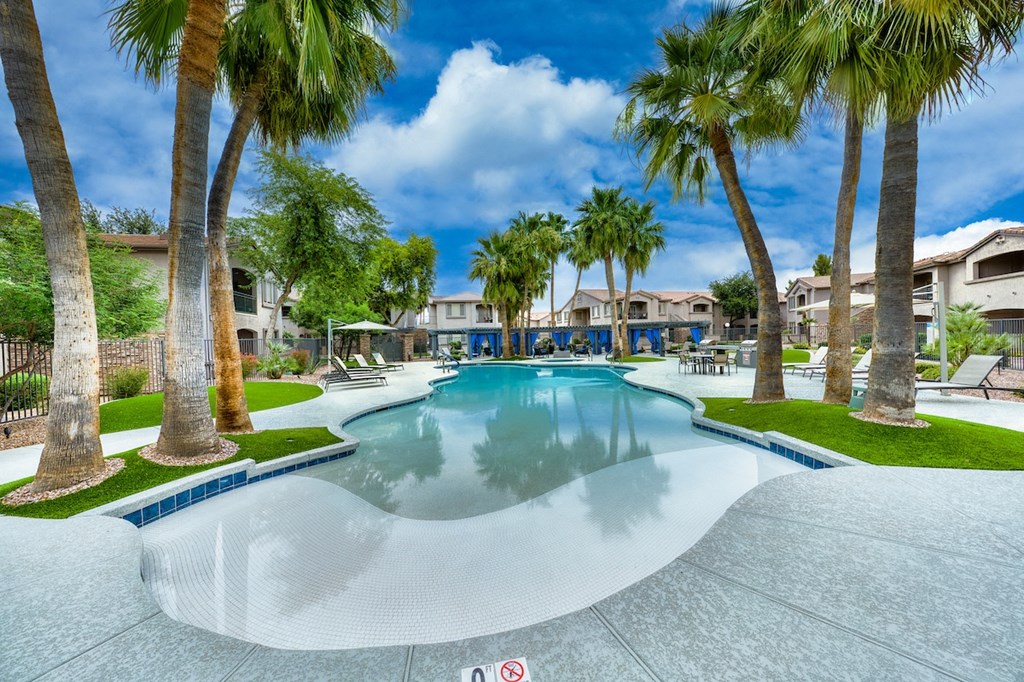 A swimming pool surrounded by palm trees and a no swimming sign.