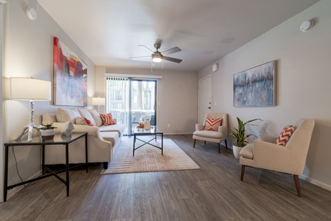 A living room with a white couch, a chair, and a table with a vase on it.
