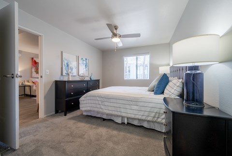 A bedroom with a bed, dresser, and ceiling fan.