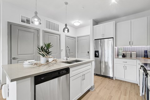 A modern kitchen with white cabinets and a wooden floor.