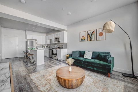 a living room with a green couch and a kitchen in the background