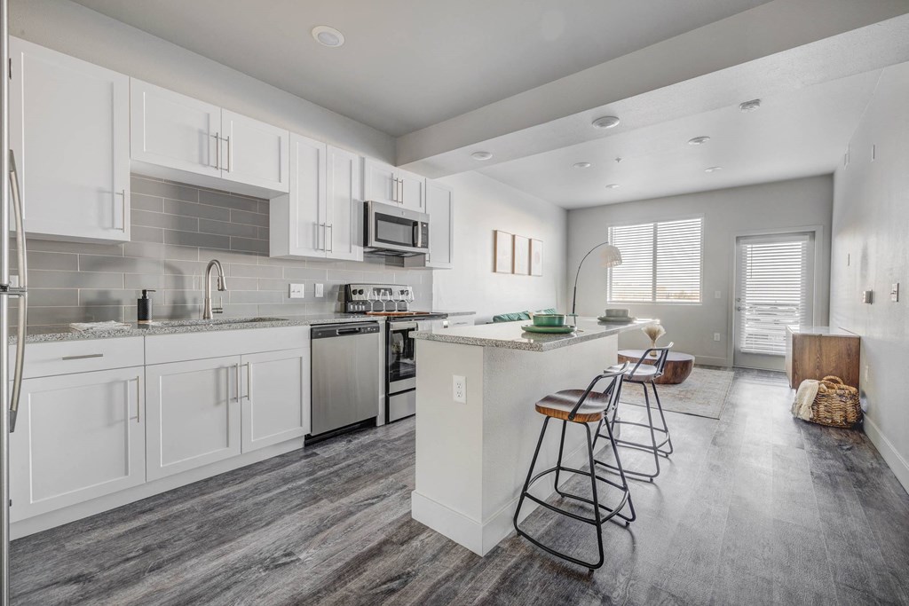 a kitchen with white cabinets and a bar with stools