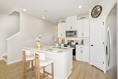 A kitchen with white cabinets and a wooden table.