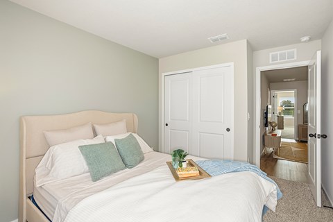 A bedroom with a large bed and a tray with a plant and a book on it.