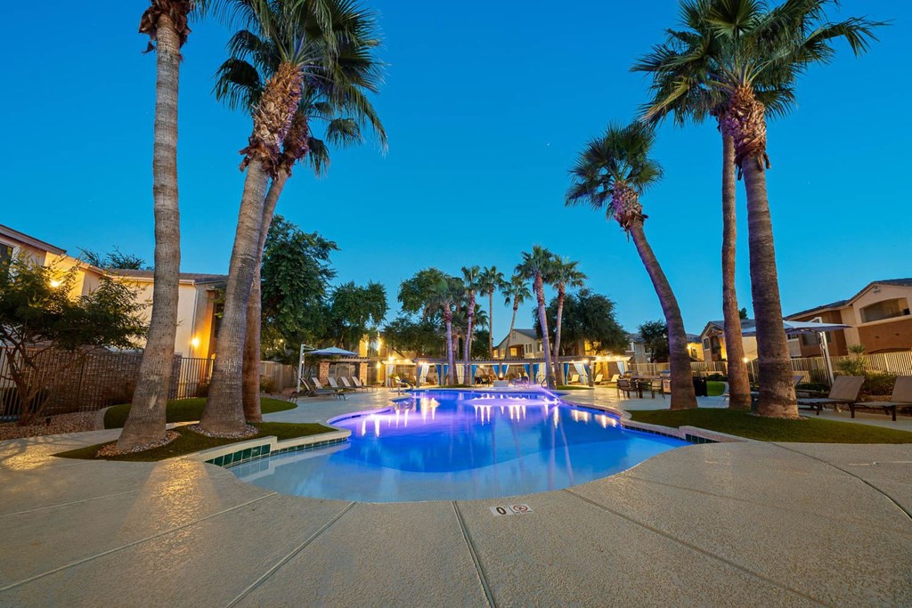 a large pool with palm trees around it at night