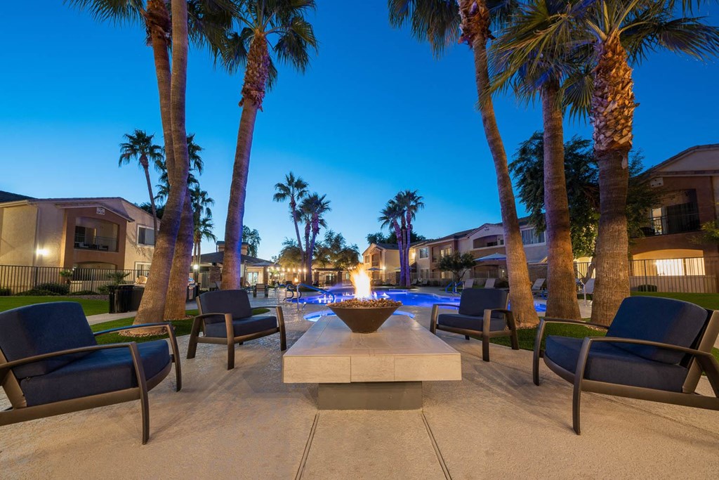 a fire pit with chairs and palm trees at night