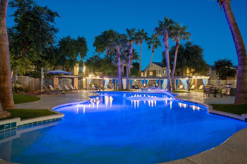 a large pool with palm trees around it at night