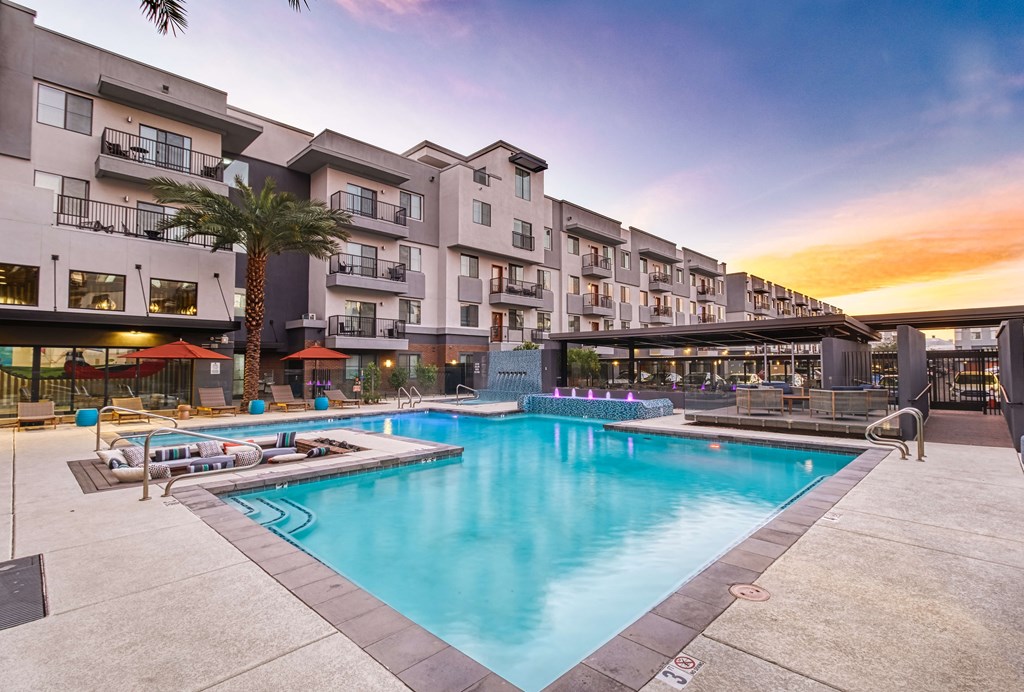 A large swimming pool is surrounded by apartment buildings.