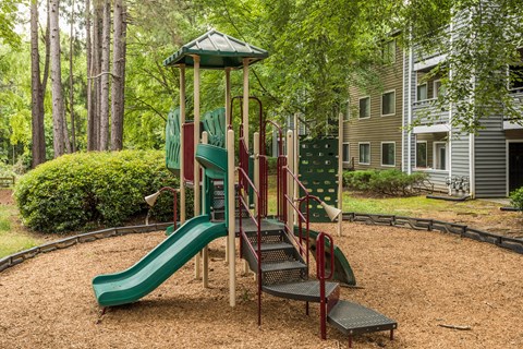 A playground with a green slide and a red and green play structure.