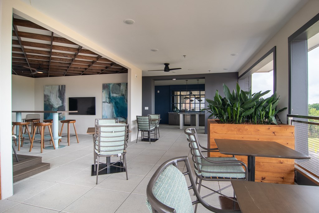 a patio area with tables and chairs and a large window