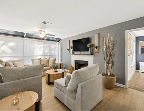 A living room with a grey couch, a white armchair, a wooden coffee table, and a fireplace.