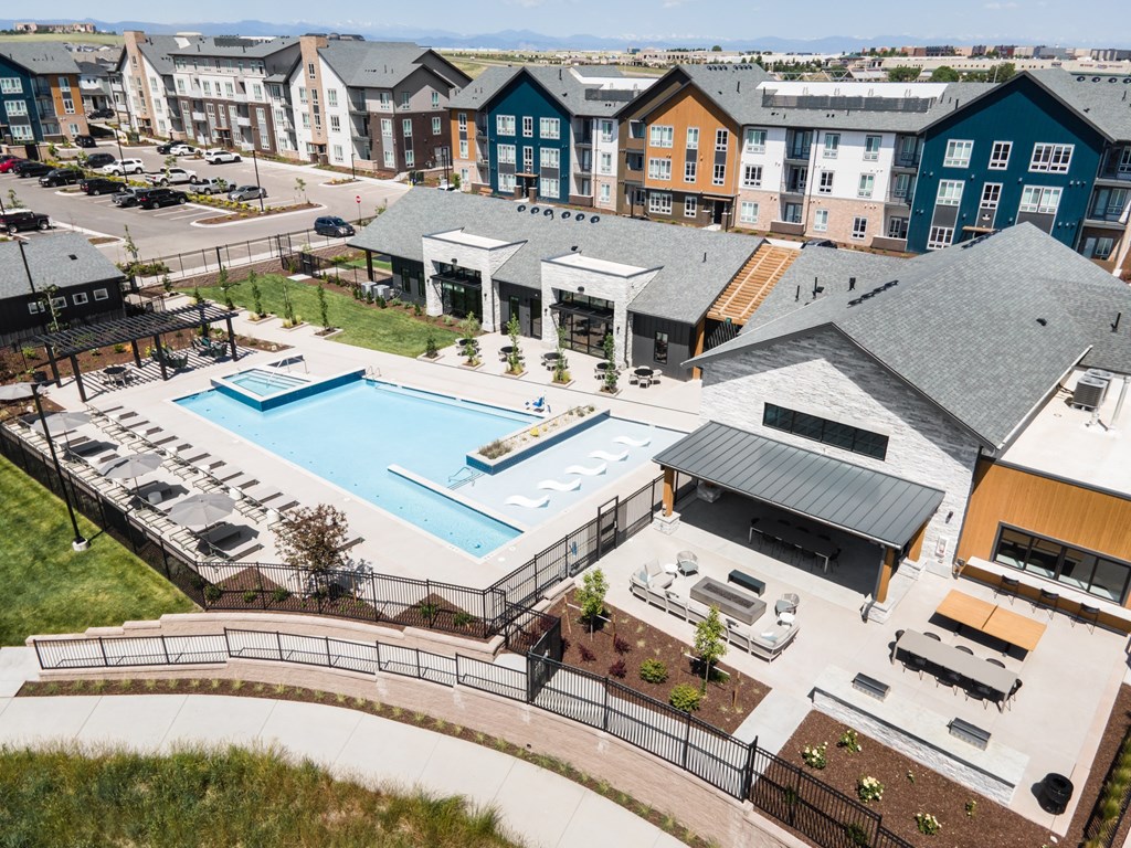 A large outdoor swimming pool surrounded by a black fence and a small building.