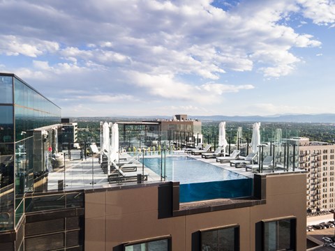 A glass building with a pool on the roof.