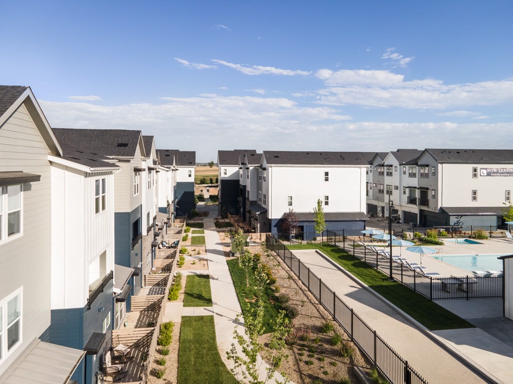 A row of houses with a pool and a fence in the foreground.