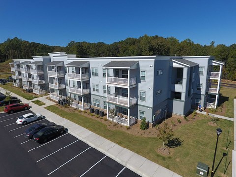Apartment complex with a parking lot in front.