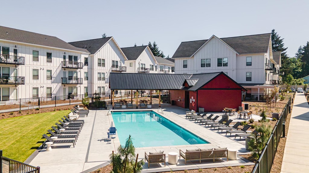 a swimming pool is surrounded by chairs in front of an apartment building at The Farmstead, Vancouver, WA