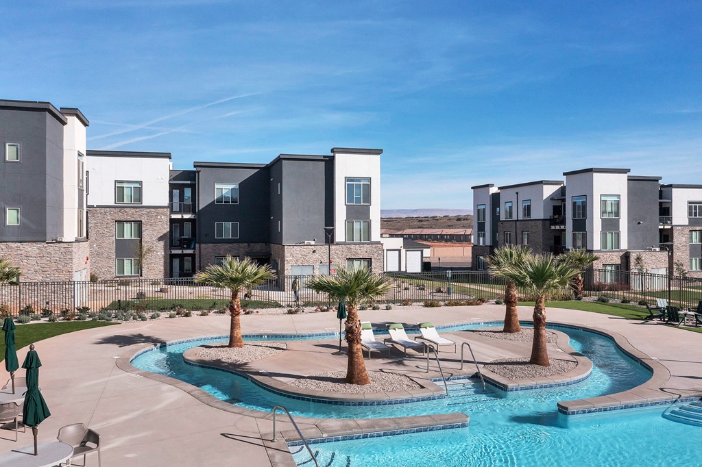 an outdoor pool with palm trees in front of an apartment building