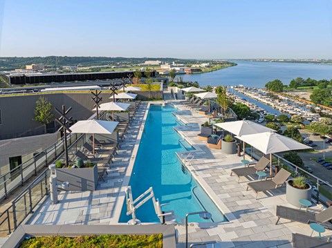 A large outdoor swimming pool with sun loungers and umbrellas.