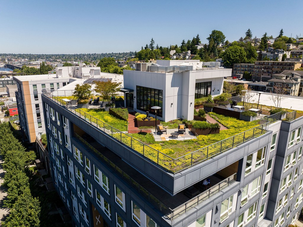 A modern building with a green roof is surrounded by other buildings.