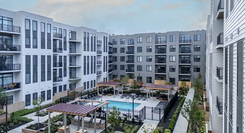 A modern apartment complex with a pool and outdoor seating area.