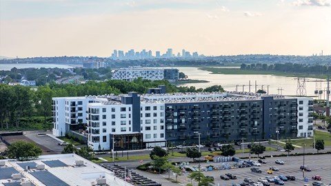 A large white and grey building with a parking lot in front of it.