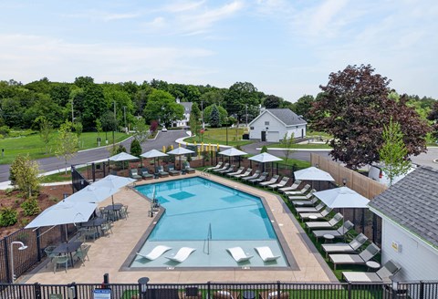 A large swimming pool surrounded by lounge chairs and umbrellas.