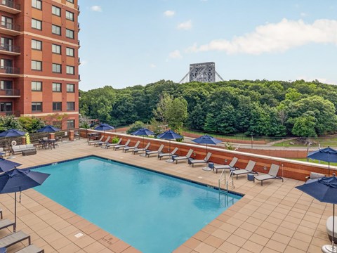 A large swimming pool surrounded by lounge chairs and umbrellas.