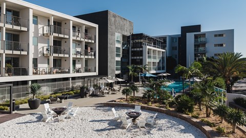 A modern building complex with a pool and outdoor furniture.