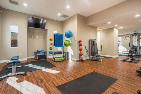 A spacious gym with a variety of equipment and a wooden floor.