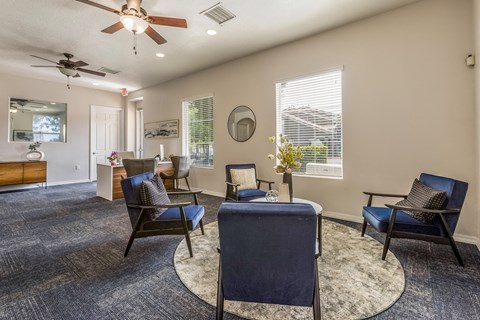 a living room with chairs and a table and a ceiling fan